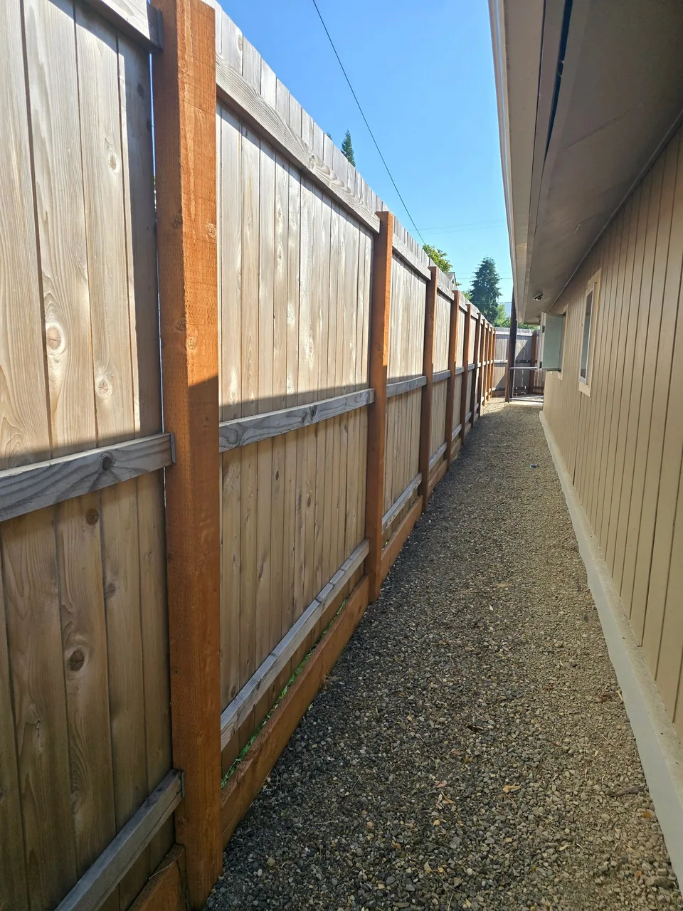 Tall cedar privacy fence along a gravel side yard