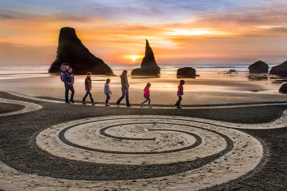 A spiral drawn in the sand on a beach at sunset